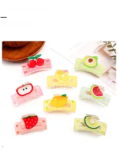Detail showing eight vibrant acrylic hair claw clips with various fruit designs and glitter