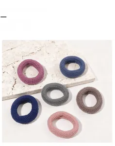 Detailed close-up of six thick elastic hair ties in Morandi colors with knit texture