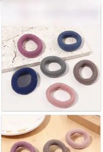 Macro detail of thick knitted elastic hair ties in various Morandi colors on stone background