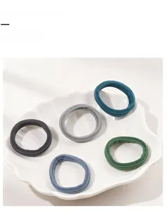 Detailed close-up of five high-elastic nylon hair ties on a white ceramic shell tray