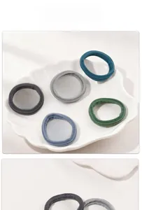 Macro shot of five seamless high-elastic nylon hair ties in various colors on a white dish