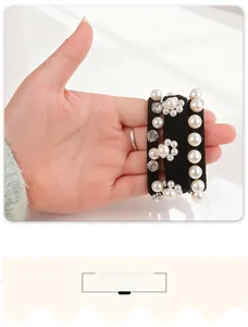 Dettaglio di elastici per capelli con perle e strass floreali mostrati sulle mani