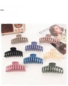 Flat lay of eight large matte hair claw clips in various colors on a white tabletop