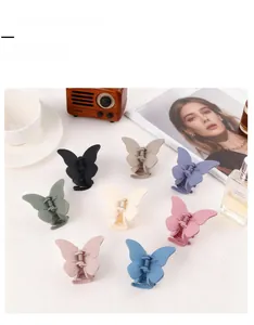 Detail view of eight colorful matte butterfly hair claw clips arranged on a white table