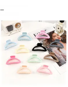 Detail view of assorted macaron hair claw clips on a white table with lifestyle props
