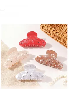 Detail view of rhinestone hair claw clips in red, beige, amber, and pearlescent white colors