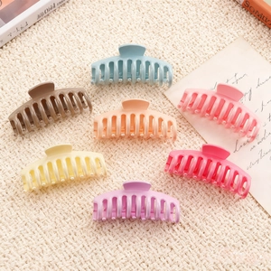 Set di 7 grandi mollette per capelli opache e colorate per donna su sfondo in maglia intrecciata