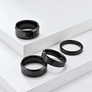 Polished black tungsten rings set with dual beveled edges on white geometric display
