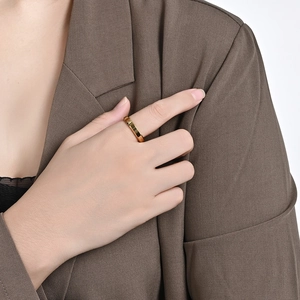 Close-up of a minimalist gold tungsten ring with faceted edges worn on a finger