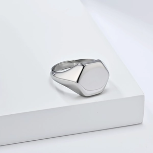 Detailed view of polished hexagonal signet ring on white minimalist pedestal
