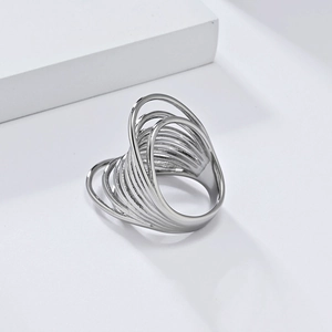 Gros plan d'une bague multicouche en acier argenté sur un support blanc minimaliste