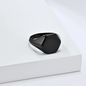 Minimalist black hexagon signet ring in titanium steel on white geometric pedestal