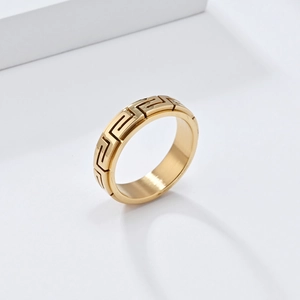 Gros plan détaillé d'une bague rotative dorée avec motif grec gravé sur fond blanc
