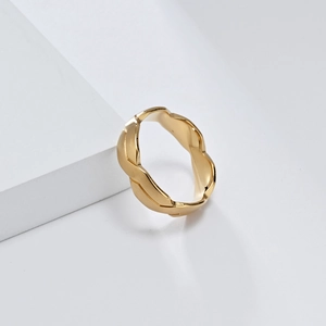 Detailansicht eines mattgoldenen, gedrehten geometrischen Rings aus Titanstahl