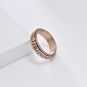 Vue macro de la bague rotative en or rose avec motif grec et finition en métal brossé