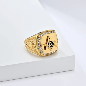 Men's gold Masonic signet ring with black G logo and sparkling crystals on white marble