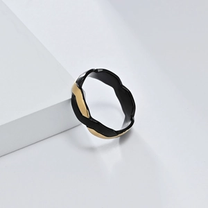Makro-Detailansicht des wellenförmigen Rings mit zweifarbiger Schwarz-Gold-Beschichtung