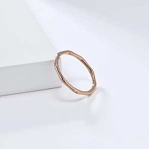 Close-up van roségouden bamboe ring met gepolijste metalen textuur op witte sokkel