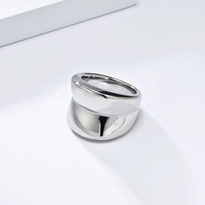 Close-up of polished silver metal ring featuring thick asymmetric layered industrial design