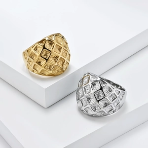 Gold and silver stainless steel wide rings with geometric grid texture on white platforms