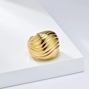 Macro shot of gold-plated wide band ring with wavy texture on white geometric stand