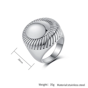 Macro detail of chunky stainless steel signet ring featuring sunburst grooved textures