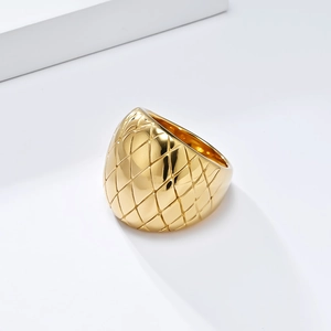 Elegant gold-plated stainless steel wide ring featuring a quilted pattern on a white stand