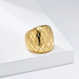 Close-up of golden stainless steel ring featuring detailed quilted pattern on a white pedestal