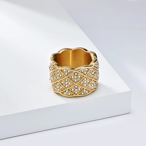 Détail d'une bague dorée avec motif en treillis, diamants et bords ondulés