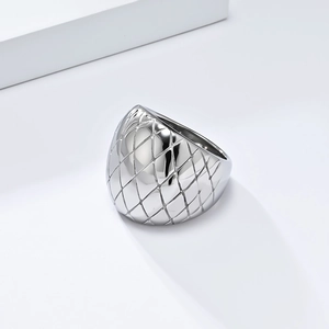 Macro detail of silver stainless steel dome ring featuring a quilted lattice pattern
