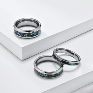 Polished tungsten steel rings set with abalone shell inlay on white geometric display stand