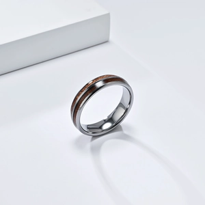 Detailed close-up of tungsten steel ring with dual wood inlay on a minimalist white stage