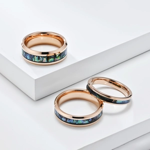 Macro detail of tungsten rings in rose gold finish with abalone shell inlay on white pedestals