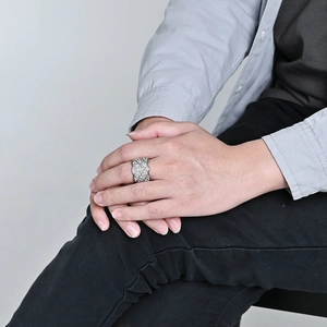 Gros plan d'une bague en maille argentée avec diamants pavés sur une main