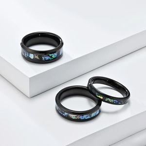 Macro shot of polished black tungsten rings featuring iridescent abalone shell inlays