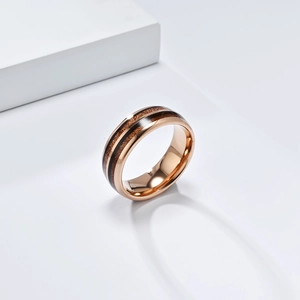 Detailed macro view of tungsten ring with rose gold finish and inlaid dark wood grain texture
