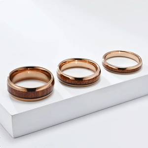 Makrodetail aus Roségold-Wolframringen mit dunkler Holzmaserung in drei Breitenstufen