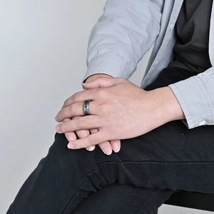 Polished black tungsten ring with vibrant abalone shell inlay worn on finger