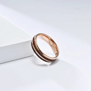 Close-up of rose gold tungsten ring with centered dark wood inlay and polished finish