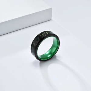 Close-up of matte black titanium steel ring with green inlay and emerald accents