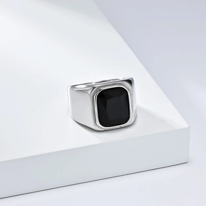Détail d'une bague chevalière pour homme avec pierre noire sur socle blanc