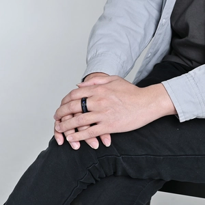 Men's black stainless steel ring with blue carbon fiber inlay on hand, modern masculine style