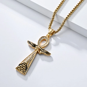 Detailed close-up of golden Ankh cross pendant with wings and rhinestones on box chain