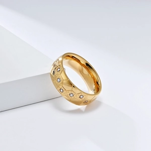 Detailed macro view of gold soccer ring with hexagonal honeycomb pattern and zircons