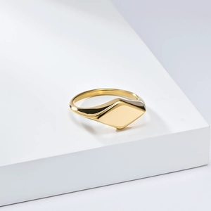 Detailansicht des geometrischen Goldrings mit polierter Oberfläche auf weißem Sockel
