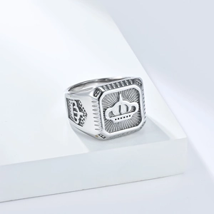 Gros plan d'une bague chevalière en argent avec motif couronne et détails radiaux