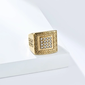 Close-up of a gold hip-hop ring with Greek key patterns and a paved diamond square face
