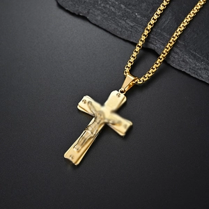 Macro detail of golden stainless steel crucifix pendant with 3D Jesus figure and box chain