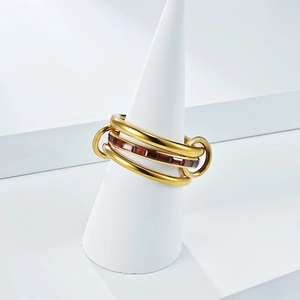 Vista macro de anillos entrelazados bañados en oro 18K con circonitas rojas