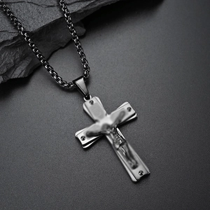 Vintage stainless steel cross necklace with Jesus crucifix pendant on a stone background